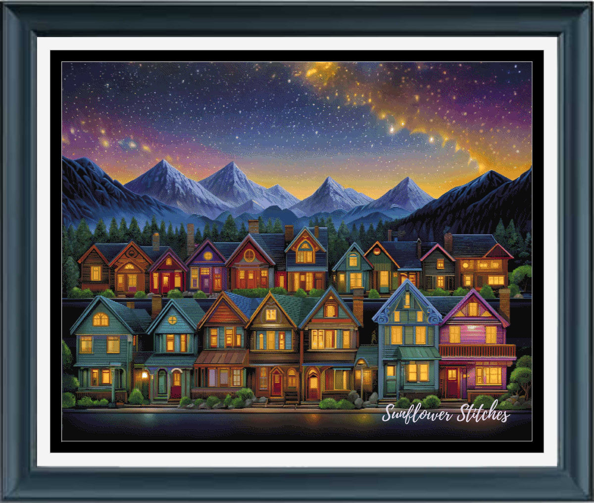 A framed art print depicting a row of cozy houses with glowing windows under a starry night sky and snow-capped mountains. The print is presented in a dark wood frame with a white mat.
