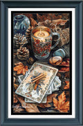 A framed still life artwork featuring a lit candle in a glass mug filled with red berries, surrounded by autumn leaves, pinecones, a blue vase, and a stack of illustrated cards on a dark tabletop. The piece is presented in a dark teal frame with a white mat.