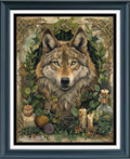 A framed cross stitch featuring a detailed illustration of a wolf surrounded by green leaves, herbs, candles, and small bottles, set within a dark frame with a white mat.