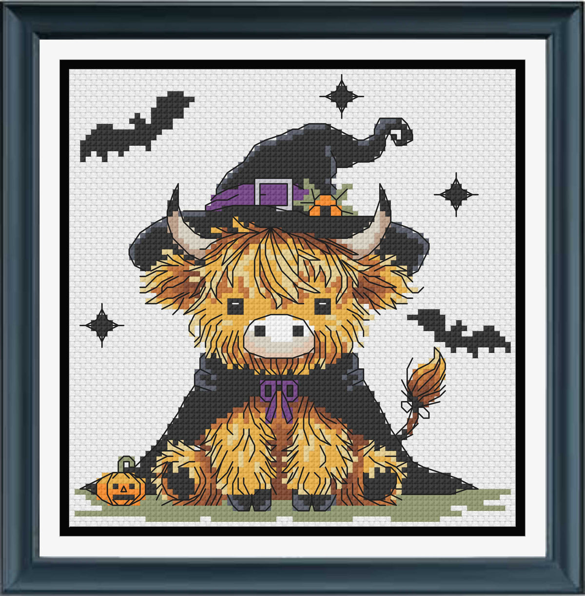 A framed cross-stitch or needlework design featuring a cute yellow-orange fluffy animal wearing a black witch hat and cape, with bats, stars, and a small pumpkin on a white stitched background 