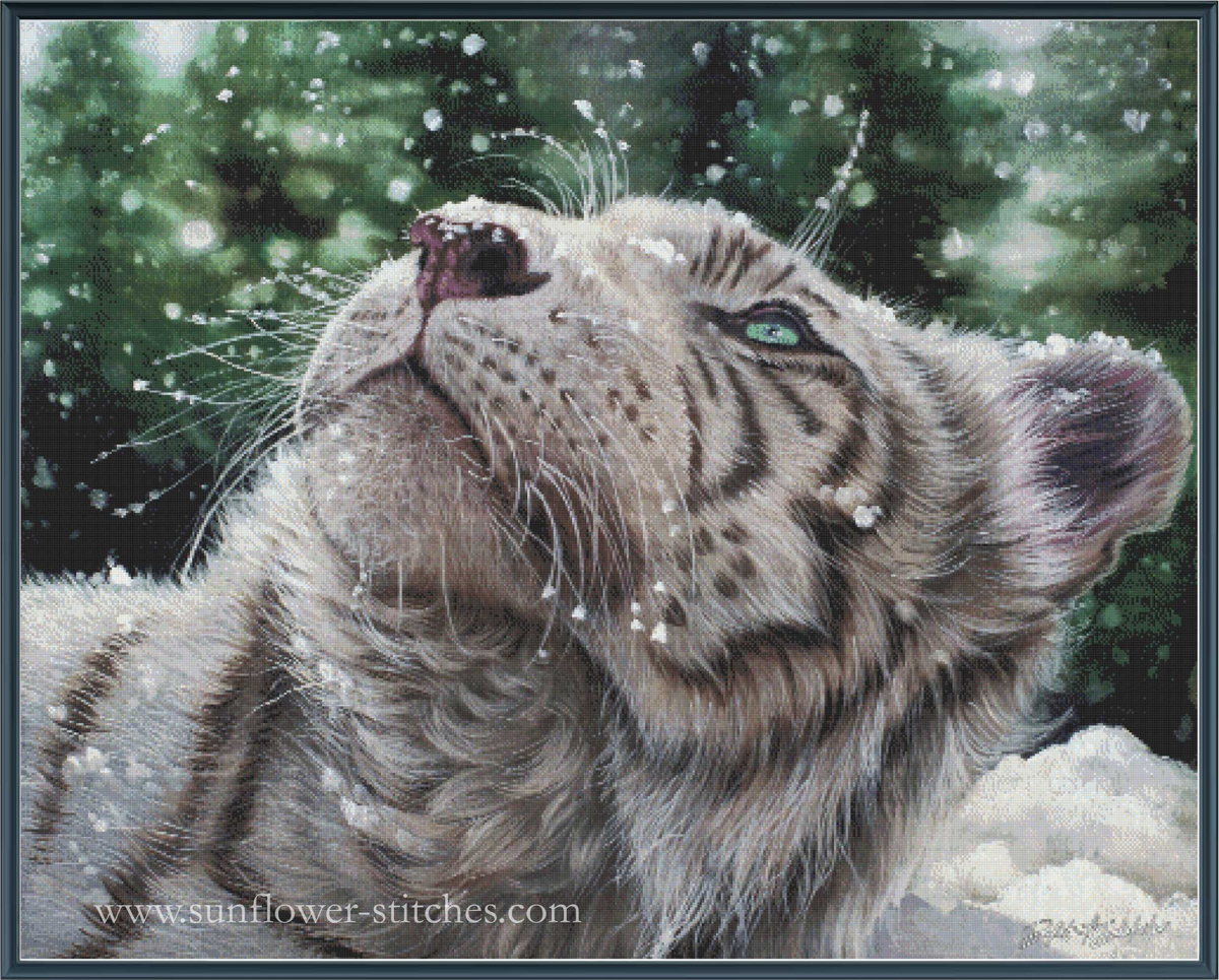 A cross-stitch pattern depicting a close-up of a white tiger cub looking upward in falling snow, with a dark green forest background. 