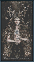Fantasy cross-stitch design featuring a female goddess with long hair, antler crown, moon symbol on forehead, heart on chest, and a wolf at her feet.